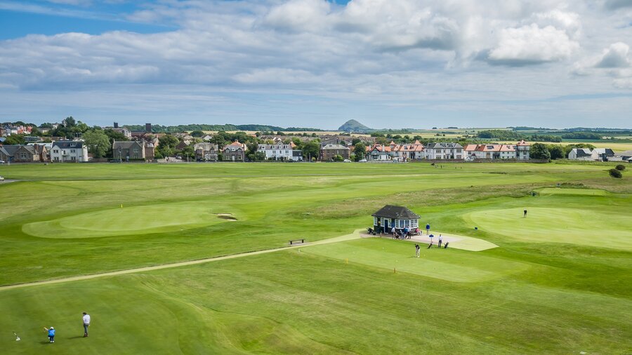 Gullane Golf Club in East Lothian - Arial view of green land with a sandy bunker with a village in the background. (© Visit Scotland)